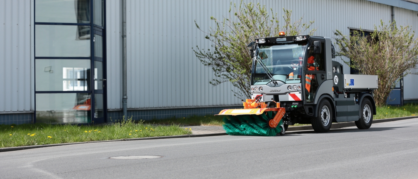 Kommunalfahrzeug nach der Erweiterung um eine Walze zum Säubern einer Straße.