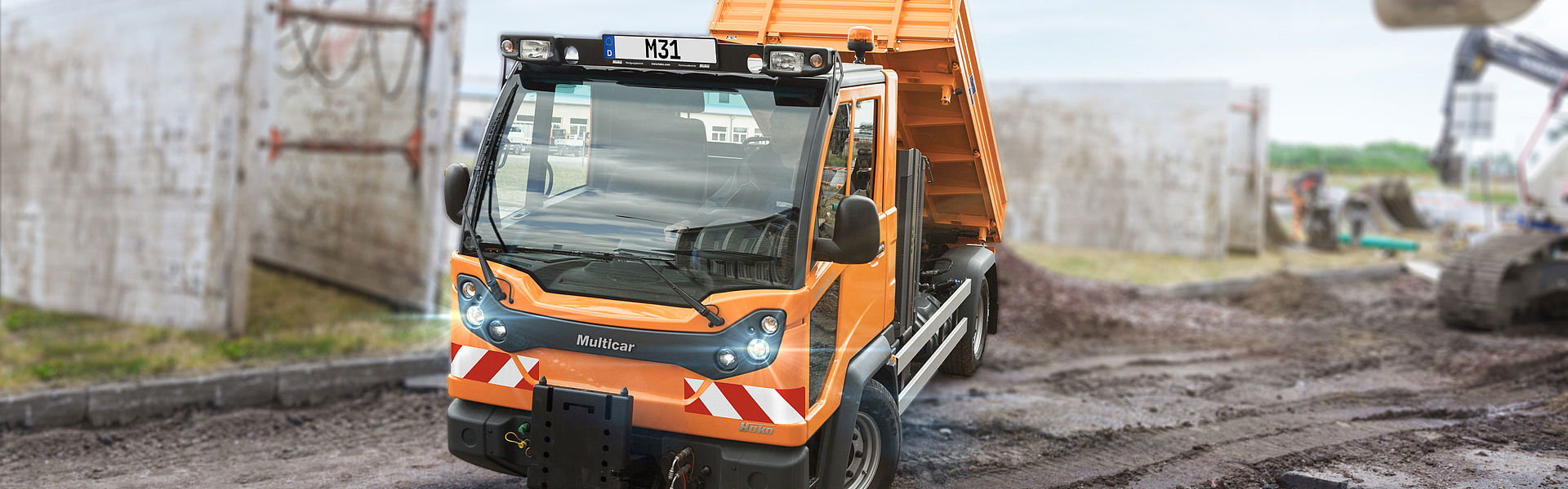Kommunaler Lasten- und Geräteträger beim Entladen auf einer Baustelle.