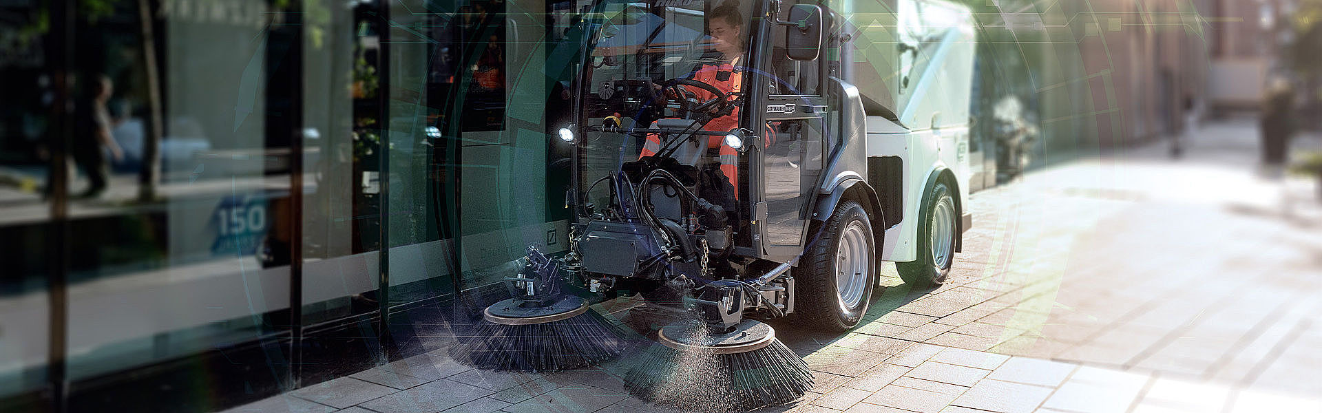 Elektrisches Kombinationsfahrzeug aus Geräteträger und Kehrmaschine säubert einen Eingangsbereich.